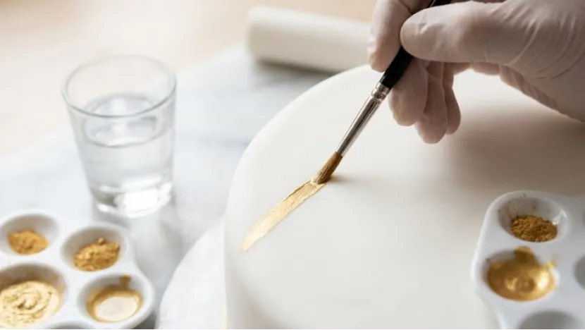 Painting gold metallic powder onto a fondant cake.