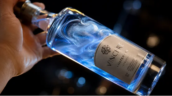 Swirling blue luster dust liqueur in a tilted bottle